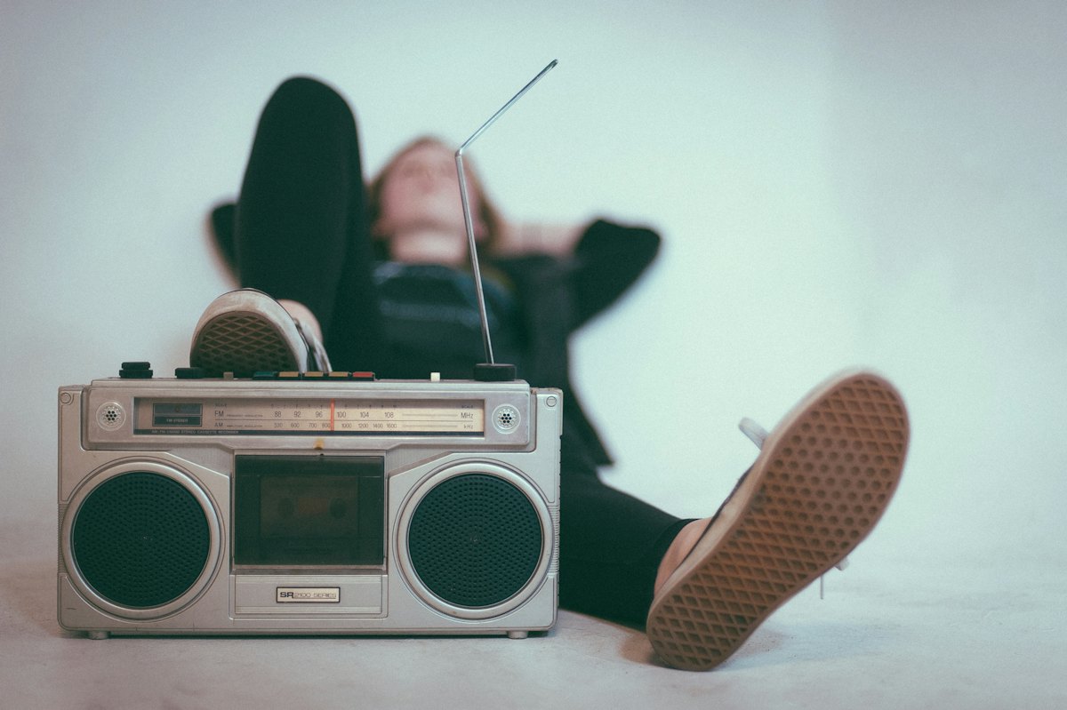 A person relaxing next to a vintage boombox