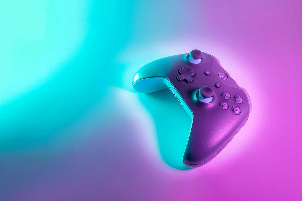 A game controller on a teal and pink gradient background