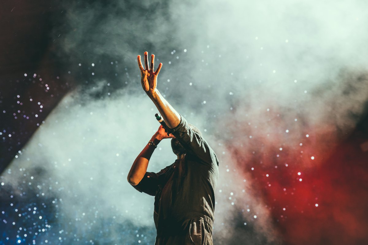 A performer with arms raised in colourful smoke