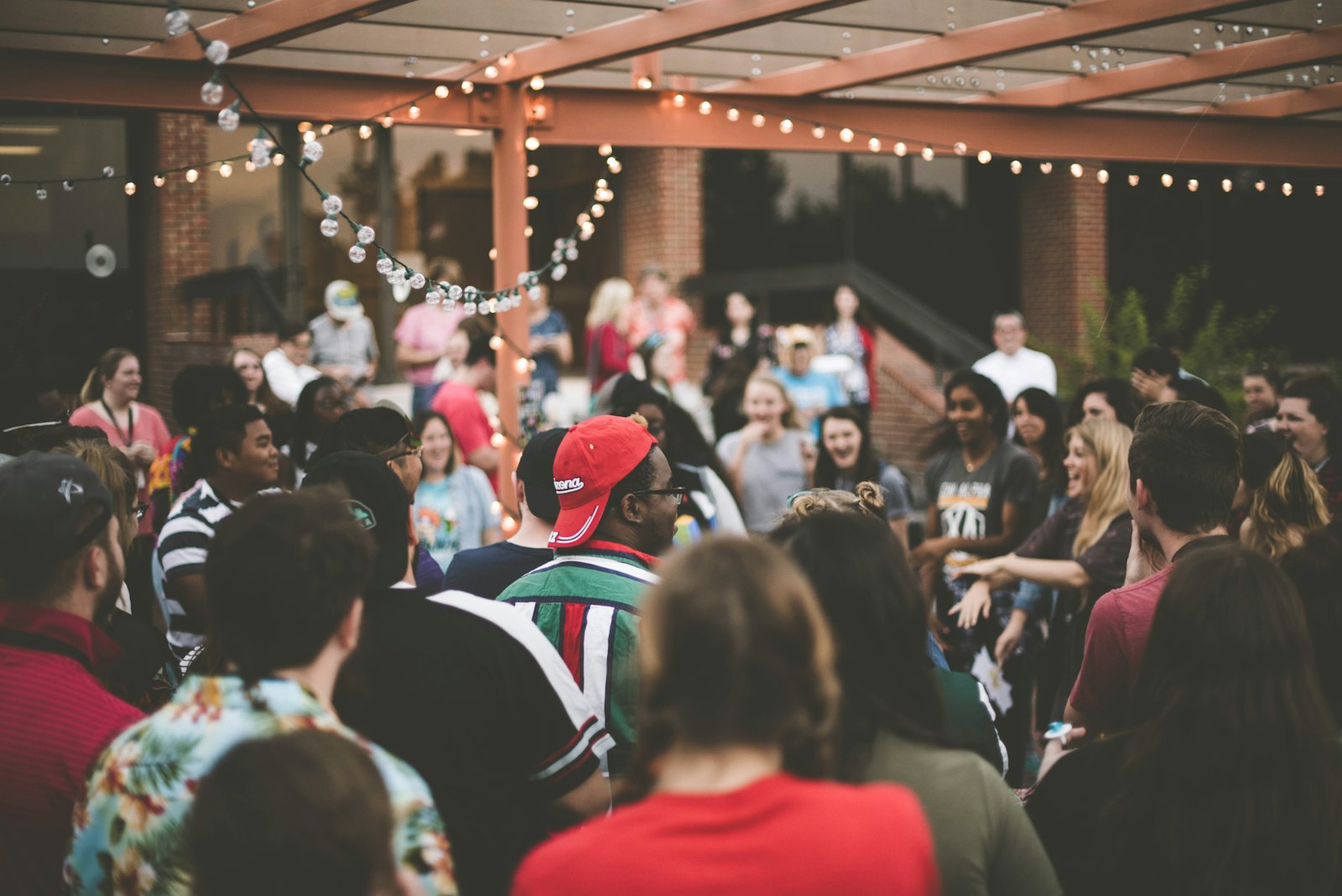 A friendly crowd gathered at an outdoor evening event under string lights