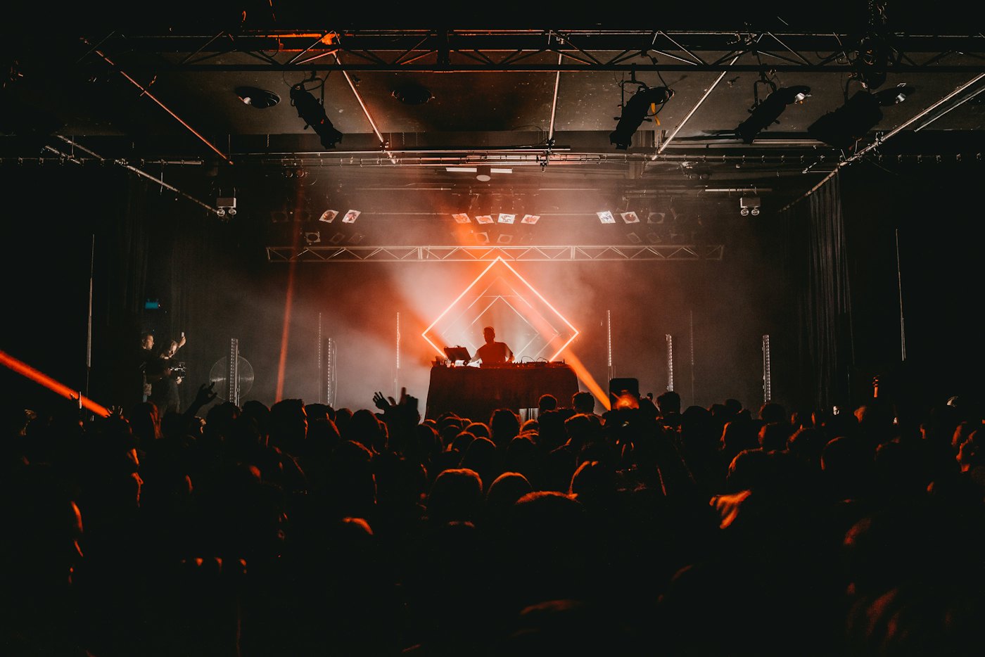 A concert stage framed by lighting truss above a crowd