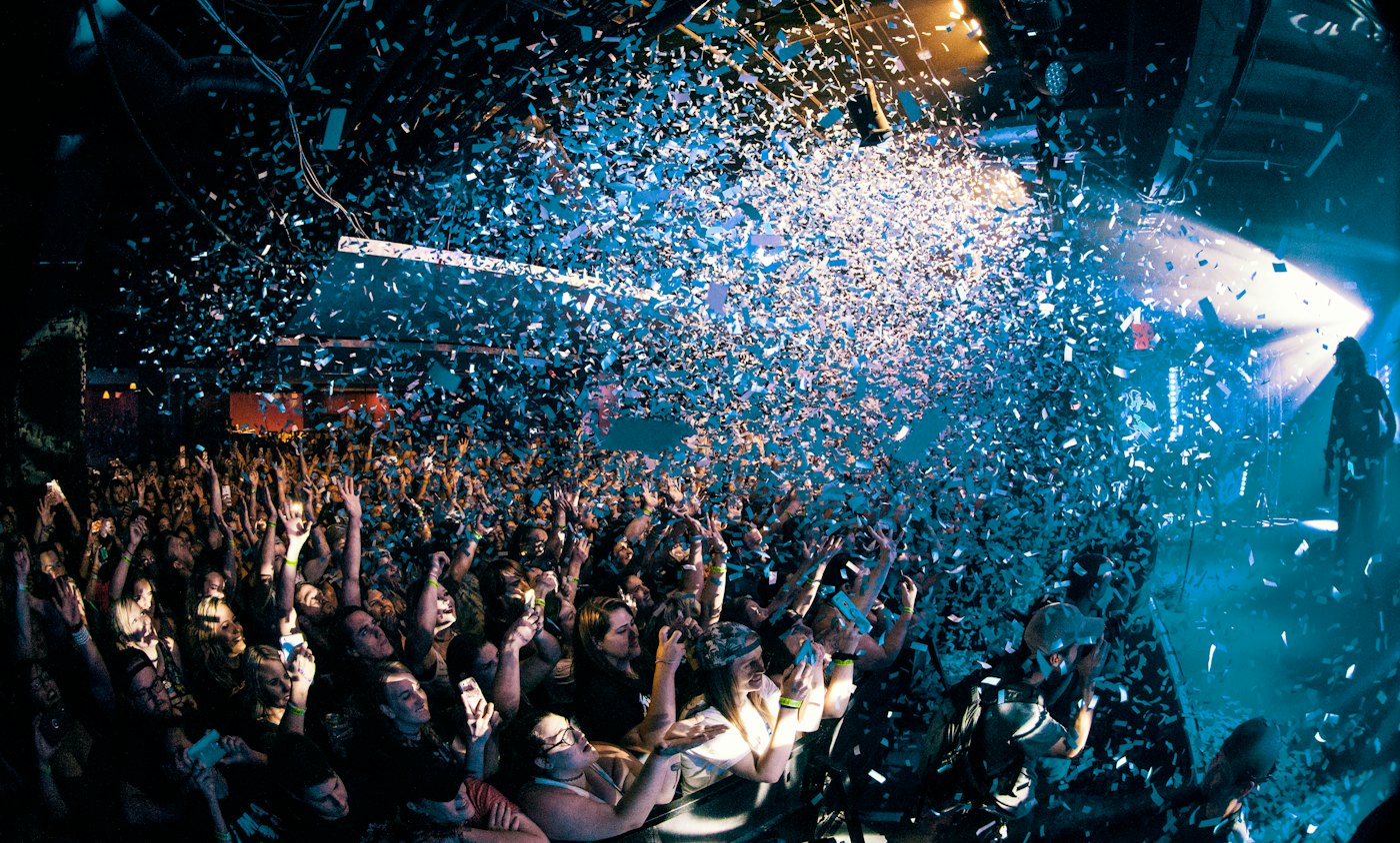 Confetti falling over a crowd in blue light