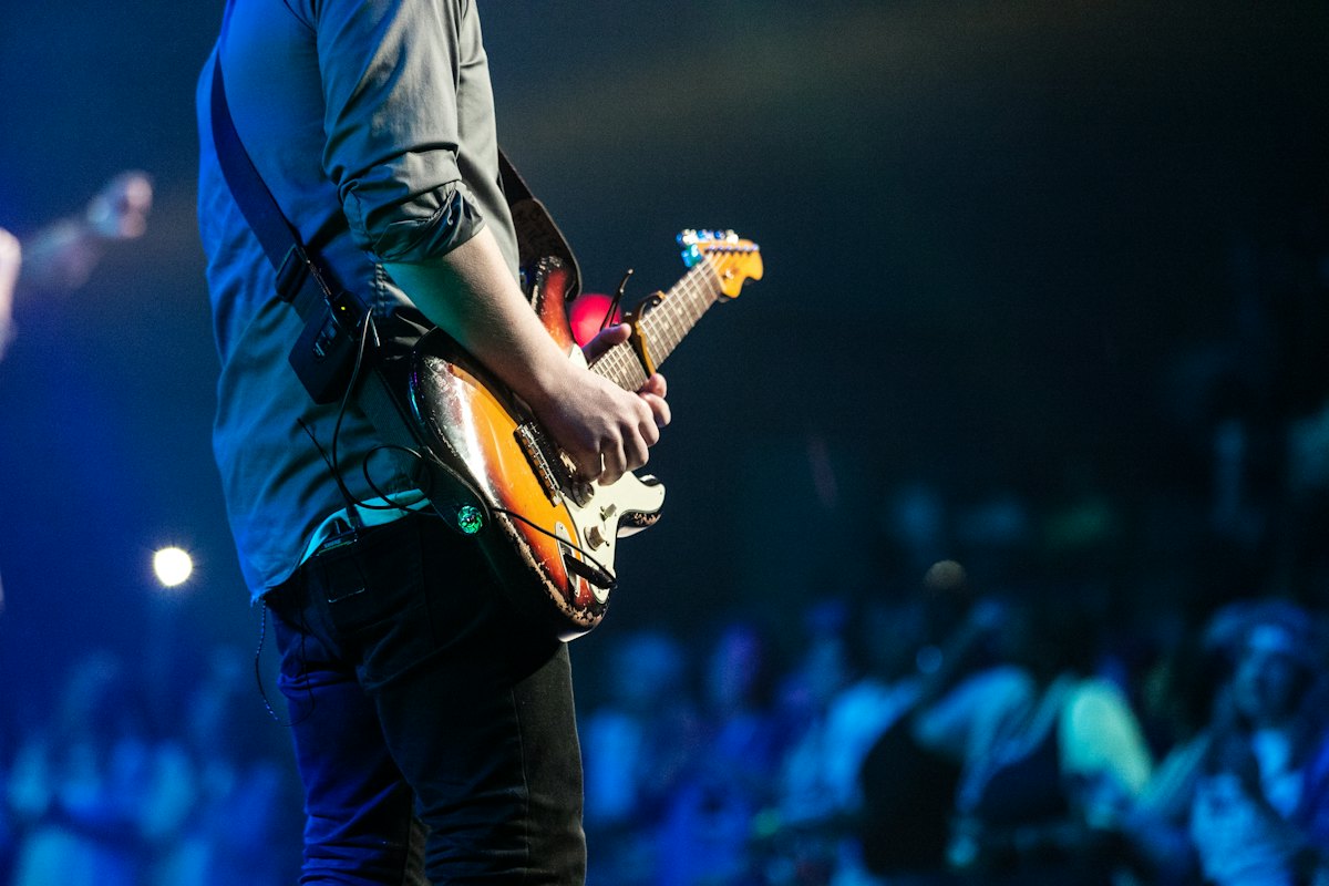 A guitarist performing on a blue-lit stage