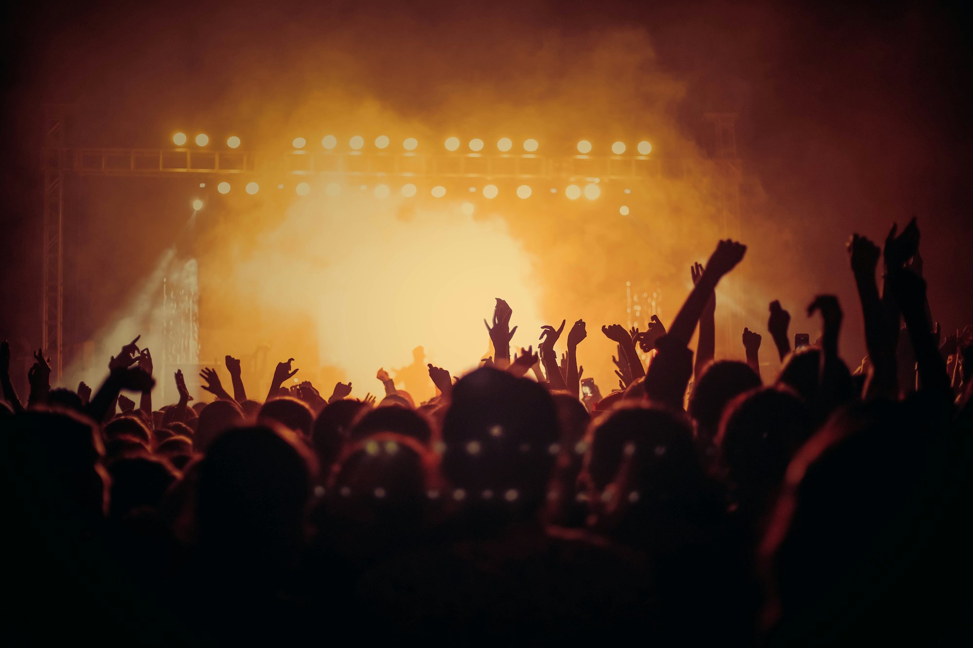 An amber-lit stage with a crowd raising their hands in the haze
